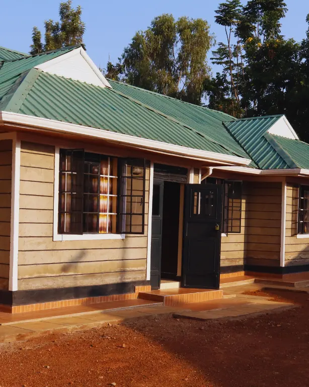 Front of a bungalow in evening light, its door open under a green roof