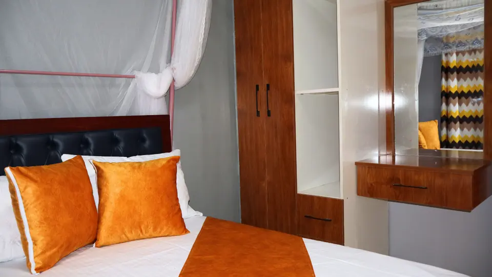 Bed with orange cushions beside a built-in wardrobe and a dressing table