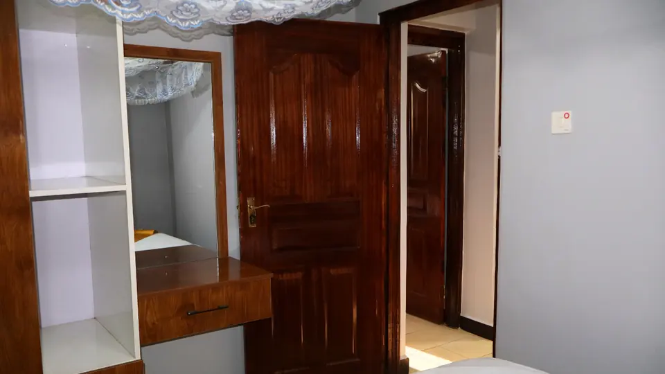 Bedroom with open wardrobe shelves, a dressing table with mirror and a wooden door