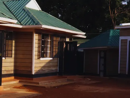 Front of a bungalow in evening light, a green-roofed outbuilding beside it