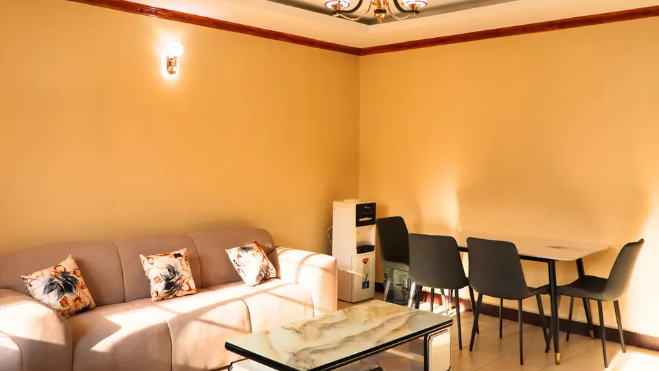 Sitting room with a sofa, coffee table and a four-seat dining table by a water dispenser