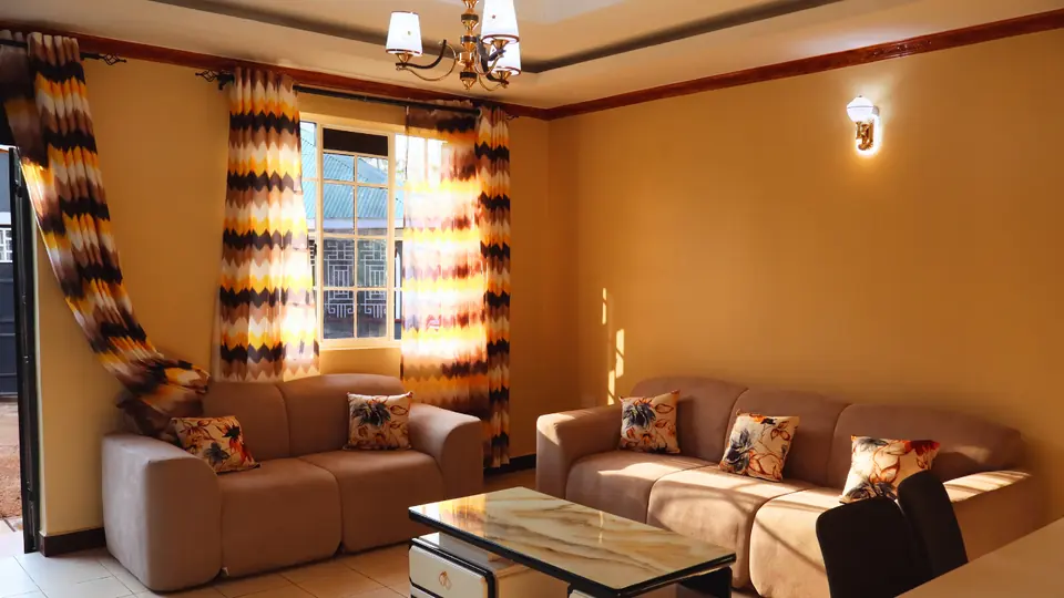 Sitting room with two sofas, a marble-top coffee table and sunlight through patterned curtains