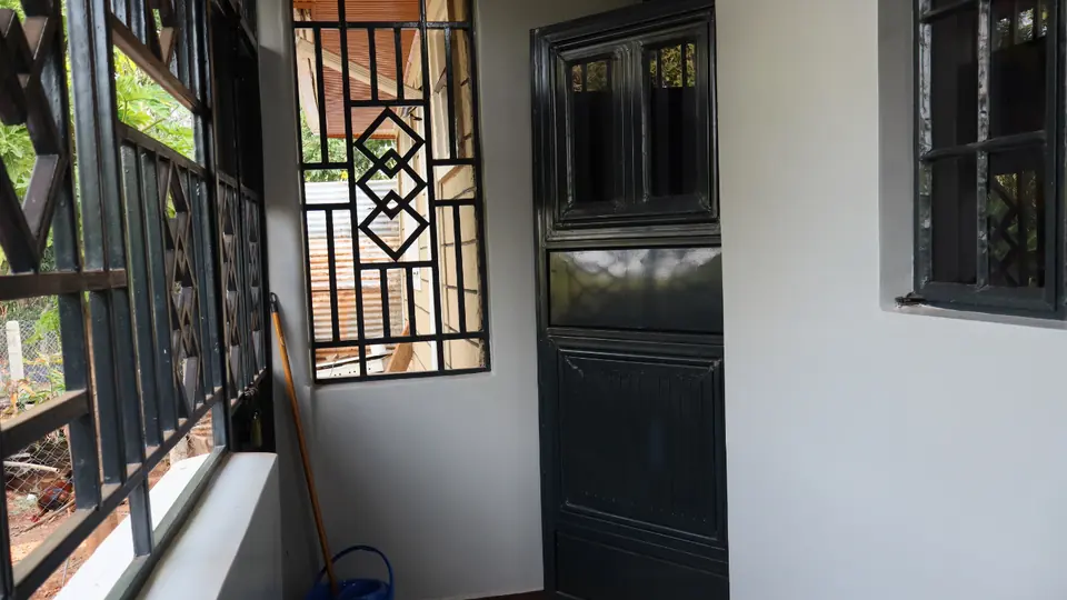 Enclosed veranda with patterned window grilles and a black front door